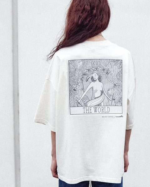A female model is wearing the White Canvas Originals sustainable, oversized, genderless t-shirt, one size. The organic cotton, natural color t-shirt has minimal modern aesthetics design allowing comfort and bringing self-confidence. This limited edition collection is made in Portugal to reduce environmental impact and guarantee high quality and durability of the products. There is an illustration by the artist Maria Robla at the back.