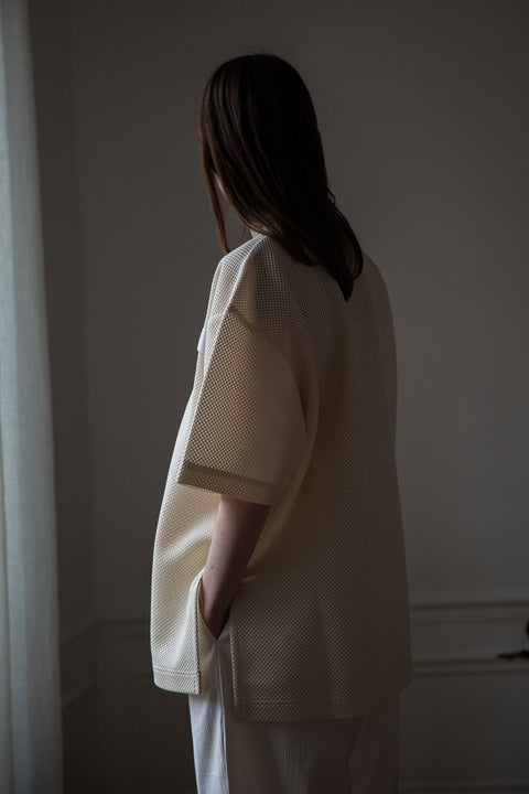 Dalva is wearing White Canvas sustainable mesh oversized, genderless, seasonless t-shirt, one size. The mesh t-shirt has minimal modern aesthetics design allowing comfort and bringing self-confidence. This unique piece is made locally in Paris to reduce environmental impact and guarantee high quality and durability of the products. 