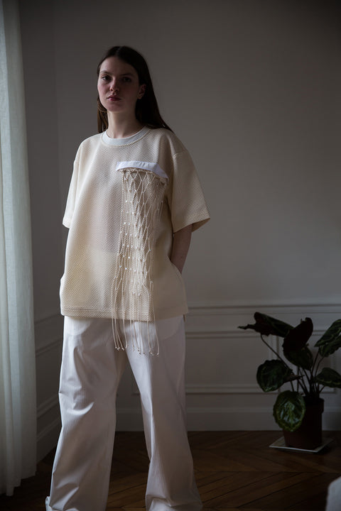 Dalva is wearing White Canvas sustainable mesh oversized, genderless, seasonless t-shirt, one size. The mesh t-shirt has minimal modern aesthetics design allowing comfort and bringing self-confidence. This unique piece is made locally in Paris to reduce environmental impact and guarantee high quality and durability of the products. 