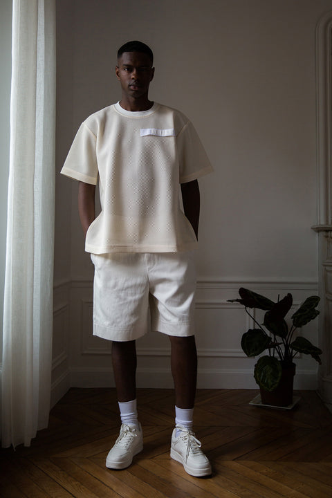 Thierno is wearing White Canvas sustainable mesh oversized, genderless, seasonless t-shirt, one size. The mesh t-shirt has minimal modern aesthetics design allowing comfort and bringing self-confidence. This unique piece is made locally in Paris to reduce environmental impact and guarantee high quality and durability of the products. 