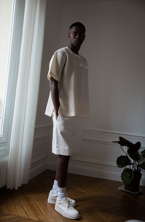 Thierno is wearing White Canvas sustainable mesh oversized, genderless, seasonless t-shirt, one size. The mesh t-shirt has minimal modern aesthetics design allowing comfort and bringing self-confidence. This unique piece is made locally in Paris to reduce environmental impact and guarantee high quality and durability of the products. 