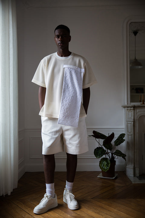 Thierno is wearing White Canvas sustainable mesh oversized, genderless, seasonless t-shirt, one size. The mesh t-shirt has minimal modern aesthetics design allowing comfort and bringing self-confidence. This unique piece is made locally in Paris to reduce environmental impact and guarantee high quality and durability of the products. 