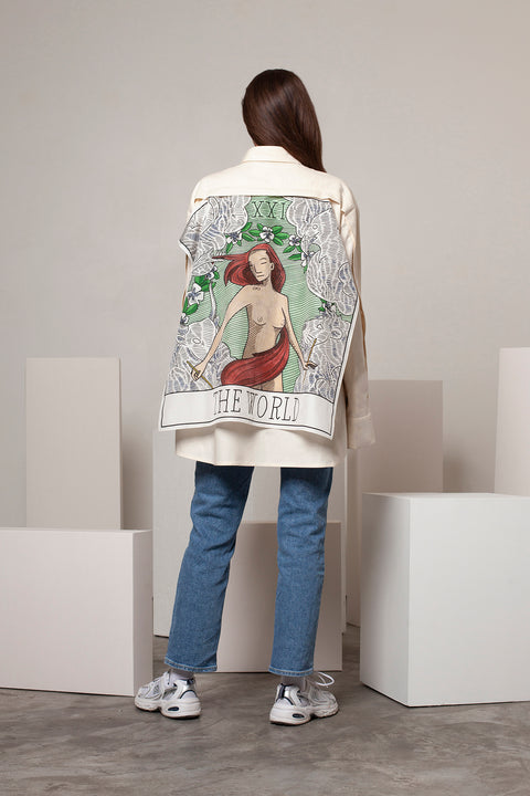 Léa is wearing the White Canvas ESSENTIAL SHIRT styled with THE WORLD foulard and square panel made from leftover deadstock silk fabric. The foulard has an exclusive design inspired by tarot cards drawn by the artist Maria Robla, printed with black artisanal eco-friendly ink locally in Paris and hand painted by the artist. Wear the foulard alone or attach it to the essential pieces to personalize them and wear them your unique way. Your perfect summer accessory. White Canvas x Maria Robla.