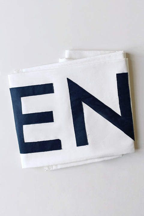 Folded White Canvas scarf in natural cotton color made from leftover deadstock fabrics and with black patched IDENTITY letters. Unique piece, made in France