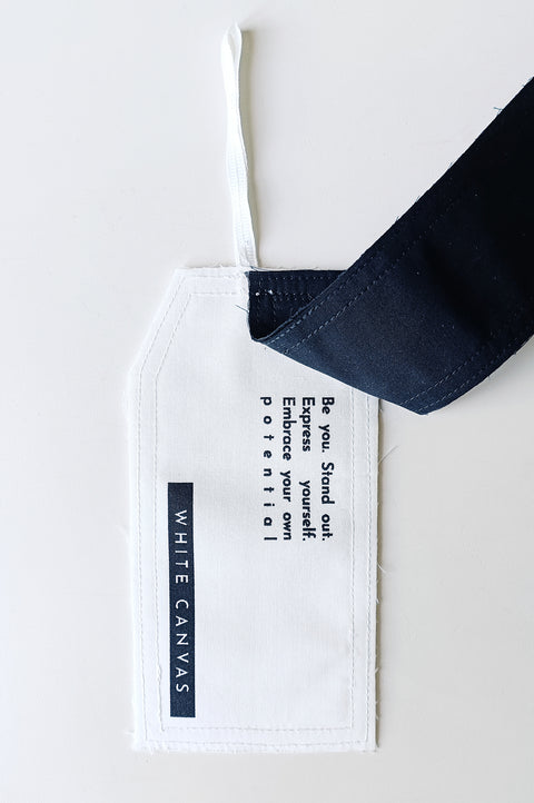 The White Canvas limited edition tag made in white and black cotton poplin leftover deadstock fabrics and with black artisanal eco-friendly screen print done locally in Paris in collaboration with RoStudio. Attach the panel to the essential pieces to personalize them and wear them your unique way. The tag is sold with key holder in recycled plastic made in collaboration with Samji Atelier