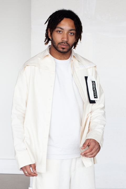The White Canvas ESSENTIAL SHIRT with a limited edition tag made in white and black cotton poplin leftover deadstock fabrics and with black artisanal eco-friendly screen print done locally in Paris in collaboration with RoStudio. Attach the panel to the essential pieces to personalize them and wear them your unique way. The tag is sold with key holder in recycled plastic made in collaboration with Samji Atelier