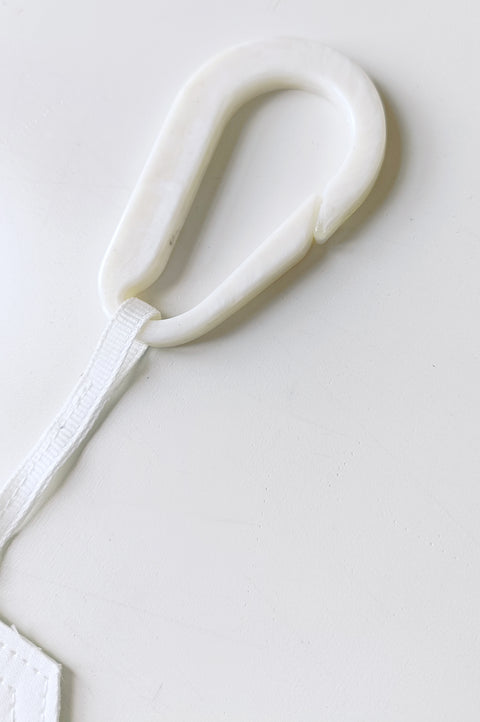 Detail. The White Canvas limited edition tag made in white and black cotton poplin leftover deadstock fabrics and with black artisanal eco-friendly screen print done locally in Paris in collaboration with RoStudio. Attach the panel to the essential pieces to personalize them and wear them your unique way. The tag is sold with key holder in recycled plastic made in collaboration with Samji Atelier