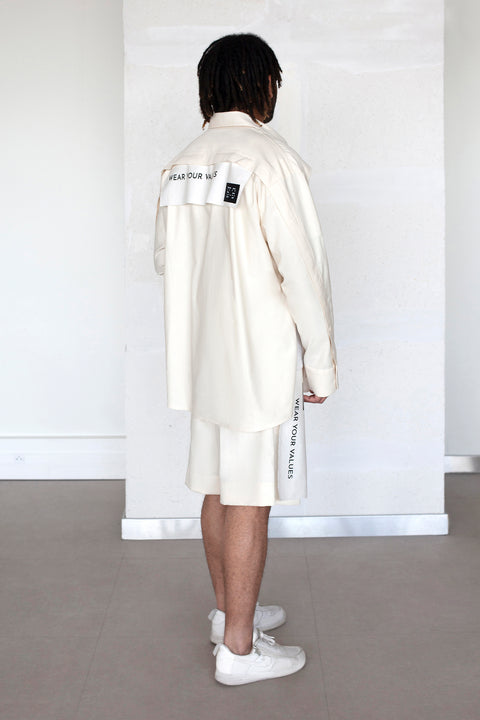 The White Canvas ESSENTIAL SHIRT with white cotton poplin fabric panel made from leftover deadstock fabrics and with black patch and artisanal eco-friendly screen print done locally in Paris in collaboration with RoStudio. Attach the panel to the essential pieces to personalize them and wear them your unique way