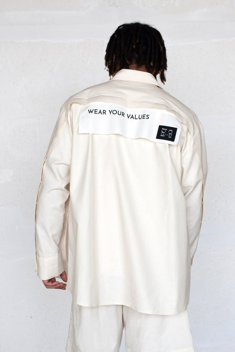 The White Canvas ESSENTIAL SHIRT with white cotton poplin fabric panel made from leftover deadstock fabrics and with black patch and artisanal eco-friendly screen print done locally in Paris in collaboration with RoStudio. Attach the panel to the essential pieces to personalize them and wear them your unique way