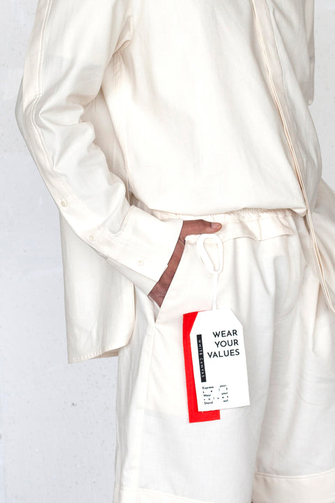 The White Canvas ESSENTIAL SHIRT and SHORT with a limited edition tag made in white and red cotton poplin leftover deadstock fabrics and with black artisanal eco-friendly screen print done locally in Paris in collaboration with RoStudio. Attach the panel to the essential pieces to personalize them and wear them your unique way. The tag is sold with key holder in recycled plastic made in collaboration with Samji Atelier