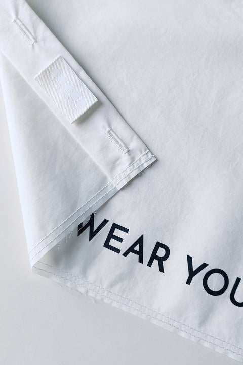 Detail. The White Canvas white cotton poplin fabric panel made from leftover deadstock fabrics and with black patch and artisanal eco-friendly screen print done locally in Paris in collaboration with RoStudio. Attach the panel to the essential pieces to personalize them and wear them your unique way
