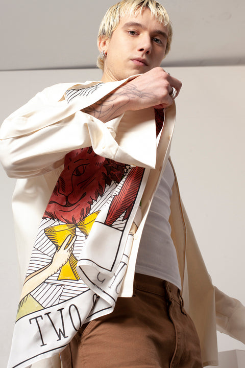 Clément is wearing the White Canvas ESSENTIAL SHIRT styled with THE TWO OF CUPS foulard and square panel made from leftover deadstock silk fabric. The foulard has an exclusive design inspired by tarot cards drawn by the artist Maria Robla, printed with black artisanal eco-friendly ink locally in Paris and hand painted by the artist. Wear the foulard alone or attach it to the essential pieces to personalize them and wear them your unique way. Your perfect summer accessory. White Canvas x Maria Robla.
