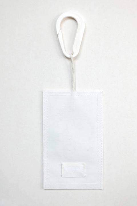 THE WORLD tag is made from leftover deadstock white cotton poplin. The black and white tag has an exclusive design inspired by tarot cards drawn by the artist Maria Robla and is printed in collaboration with RoStudio. Wear the tag alone or attach it to the essential pieces to personalize them. The tag is sold with key holder in recycled plastic made in collaboration with Samji Atelier. White Canvas x Maria Robla.